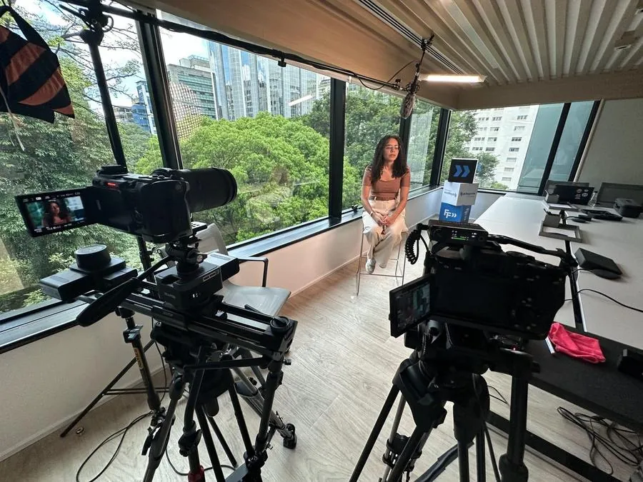 Câmeras de cinema gravando entrevista em sala com vista para a cidade