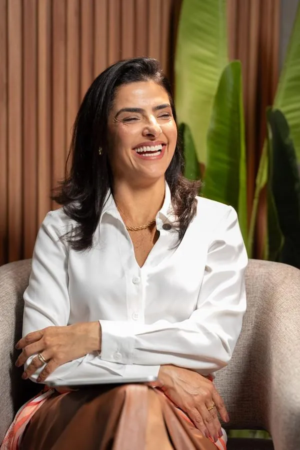 Retrato de apresentadora sorrindo no cenário do podcast Além da Boca