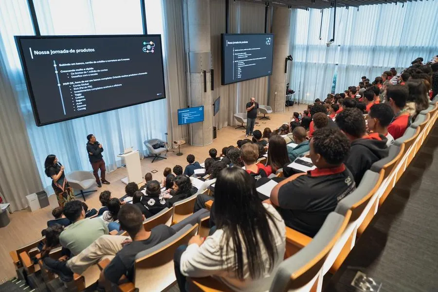 Palestra para plateia de jovens em auditório com telões no C6 Bank
