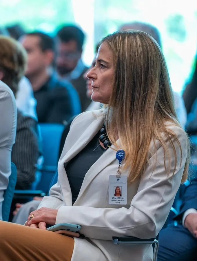 Participante com crachá sentada na plateia de evento institucional