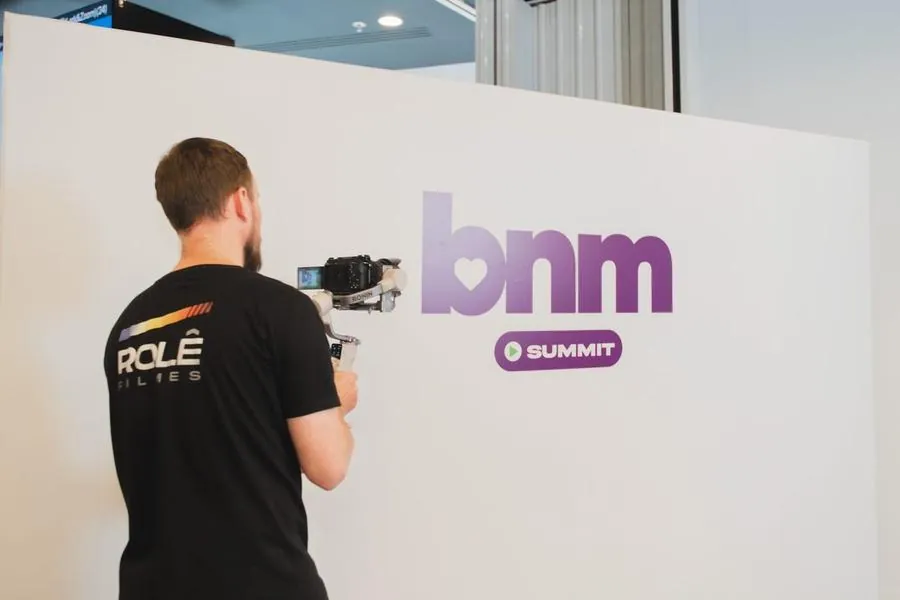Cinegrafista da Rolê Filmes gravando diante do painel do BNM Summit