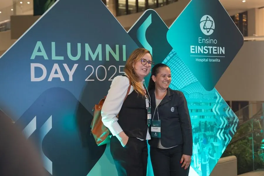 Duas participantes diante do painel Alumni Day 2025 do Einstein