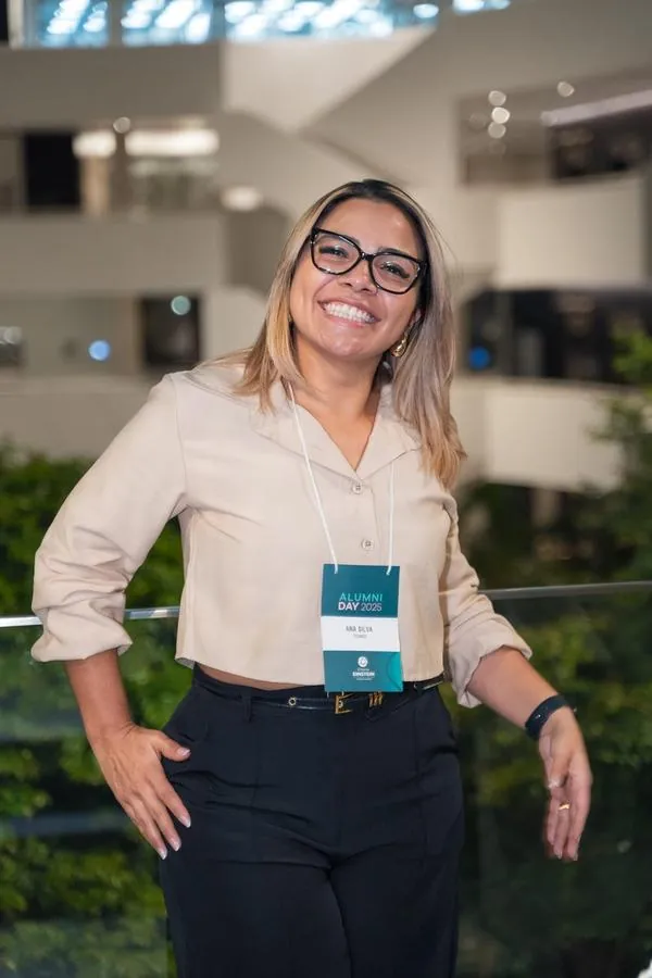 Participante sorrindo com crachá no Alumni Day do Einstein