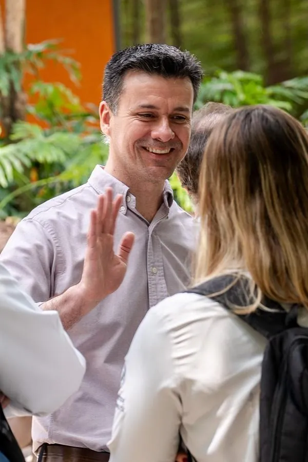 Participantes conversando e sorrindo em evento corporativo entre plantas