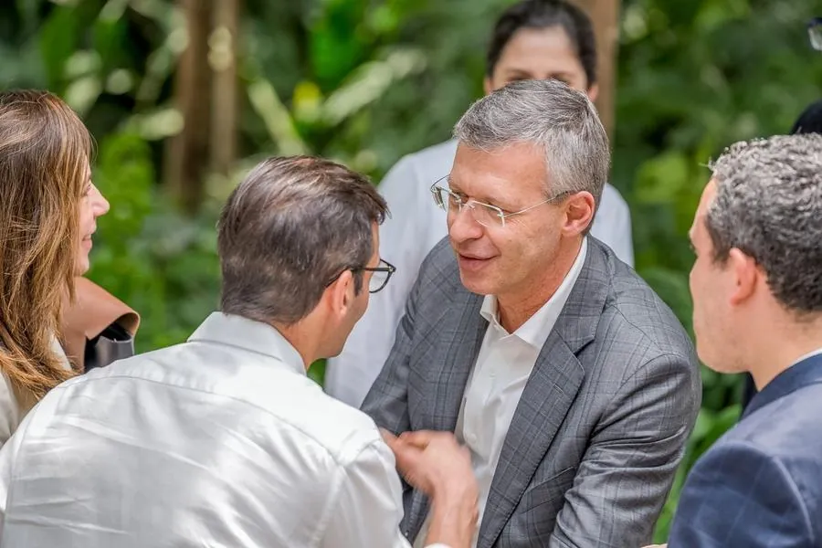 Executivos conversando em meio à vegetação durante evento corporativo