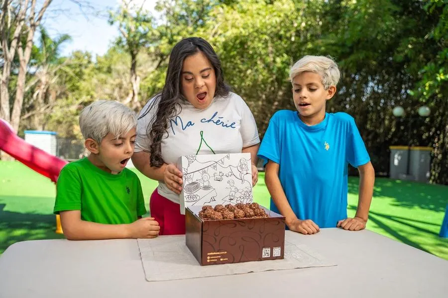 Crianças e mulher admirando caixa decorada da Sodiê Doces