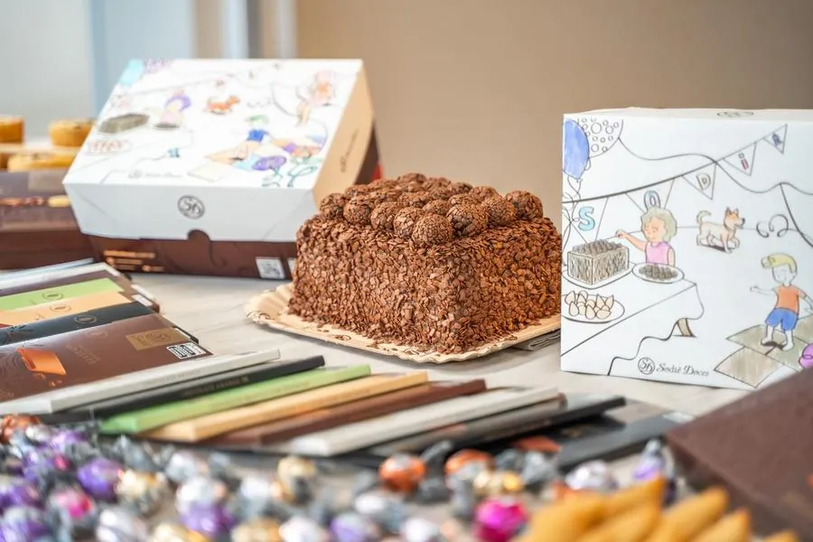 Bolo e caixas ilustradas da Sodiê Doces sobre a mesa