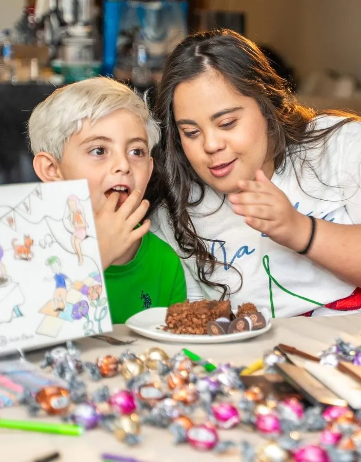 Criança e mulher com bolo e caixa decorada em campanha da Sodiê Doces