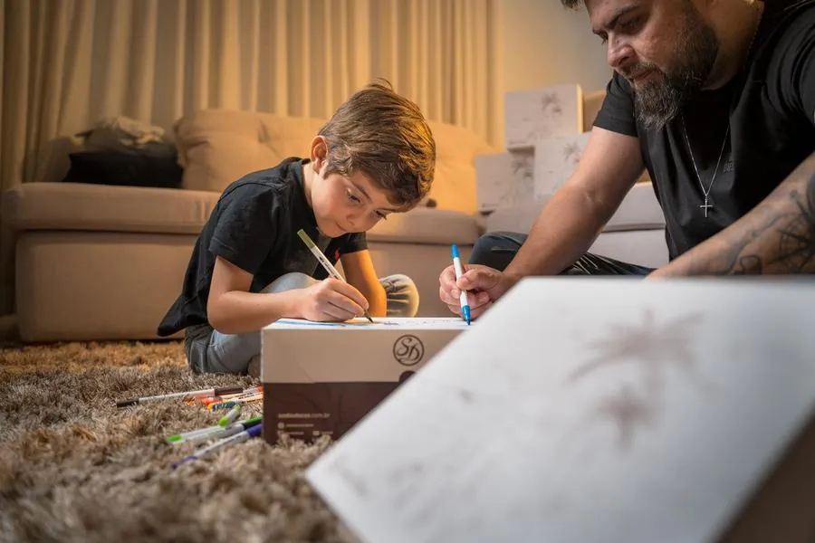 Pai e filho colorindo caixa da Sodiê Doces com canetinhas