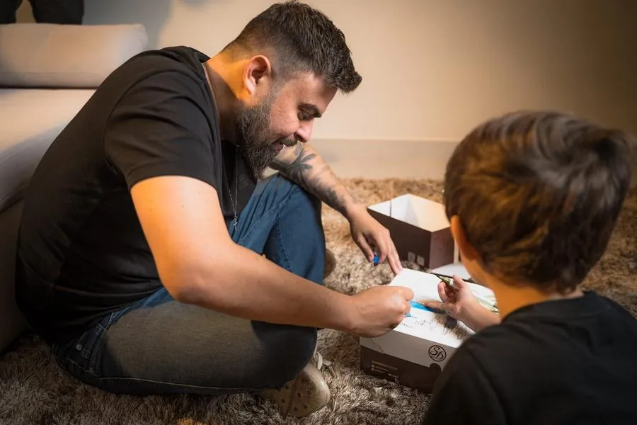 Pai ajudando o filho a desenhar em caixa da Sodiê Doces