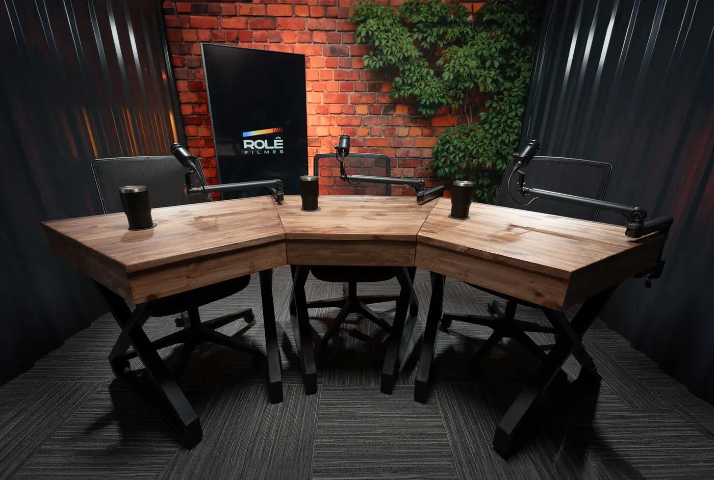 Mesa de podcast com microfones Shure e cenário de tijolo aparente com plantas, em São Paulo